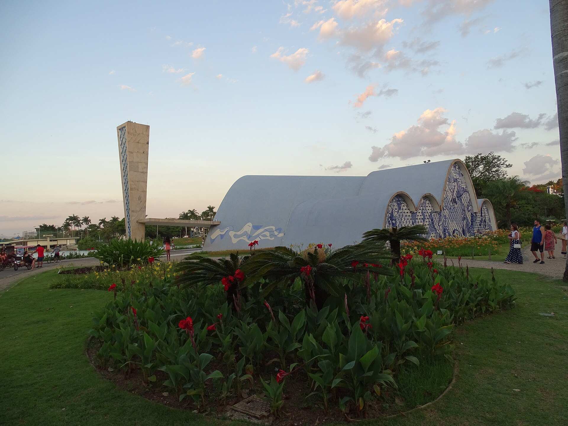 Igrejinha da Pampulha com abóbadas curvas, painel de azulejos azuis e brancos e campanário, vista do jardim