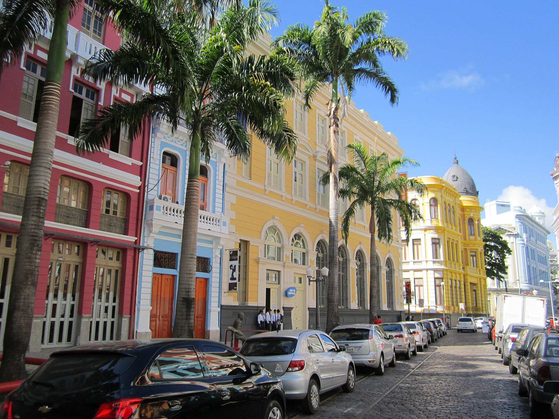 Casarões coloridos e palmeiras na Rua do Bom Jesus, no Recife Antigo, com rua de paralelepípedos